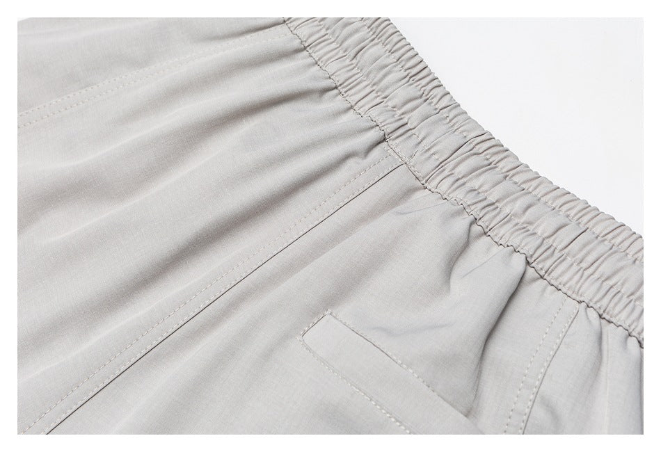 Close-up of a light-gray garment's elastic waistband, stitched seams, and pocket edge.