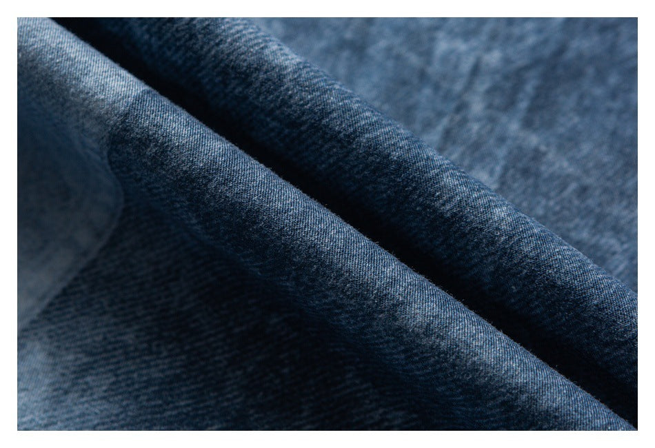Close-up of folded dark blue denim showing its textured weave and shaded folds.