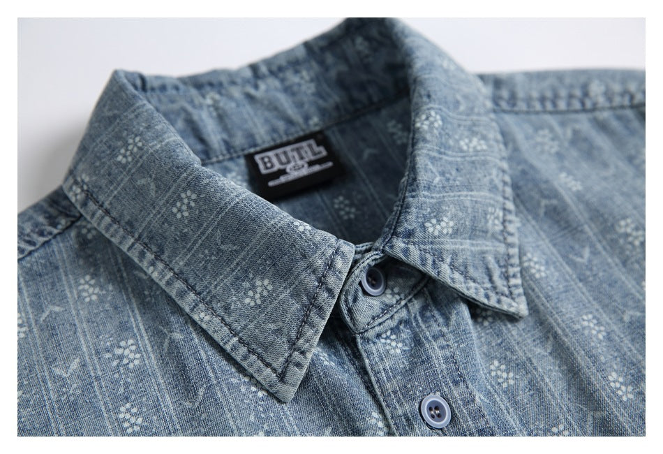 Close-up of the pointed collar and buttons on a blue-gray patterned shirt, with its sewn neck label visible.