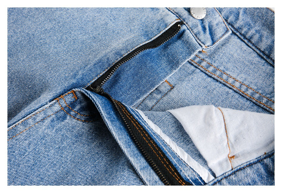 Close-up of the jeans’ open zipper fly, waistband button and inner facing in light-wash denim.
