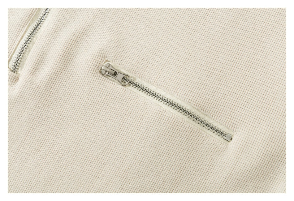 Close-up of a silver horizontal zipper pocket on ivory ribbed fabric.