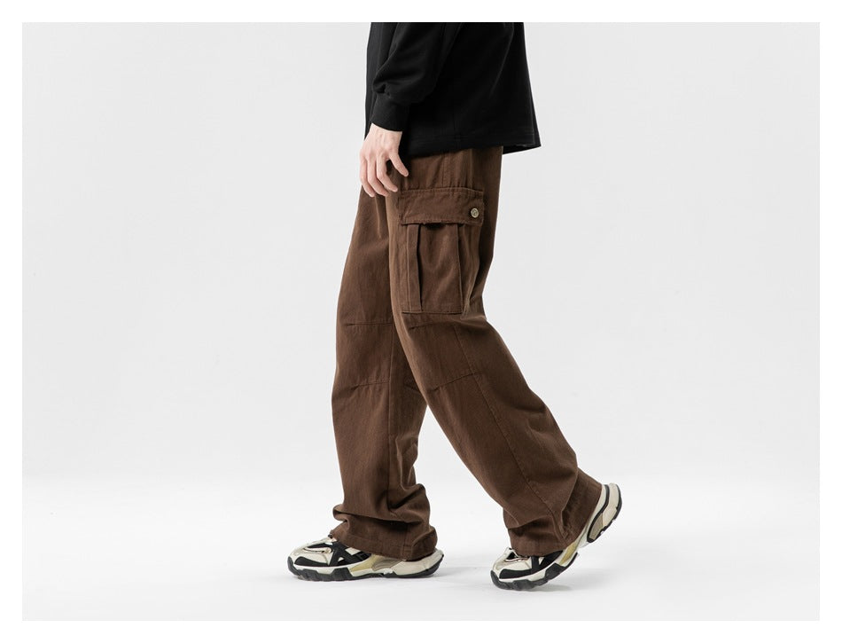 Side view of a model wearing loose brown cargo pants with a buttoned flap thigh pocket and wide legs.