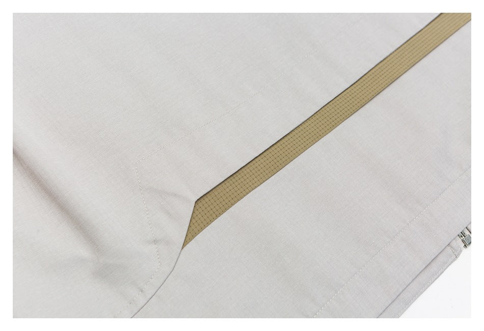 A narrow tan patterned inset runs diagonally across pale gray garment fabric.