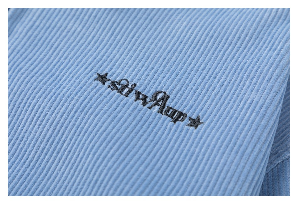 Close-up of black star-accented embroidery on the ribbed light blue jacket fabric.