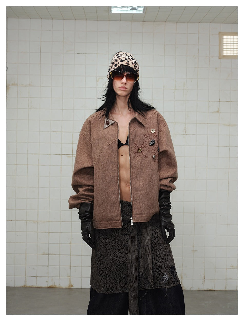 Model wearing open brown zip jacket with chest embroidery and buttons, leopard beanie, sunglasses and black gloves