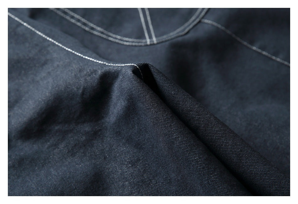 Close-up of dark denim folds and contrast stitching along a seam.