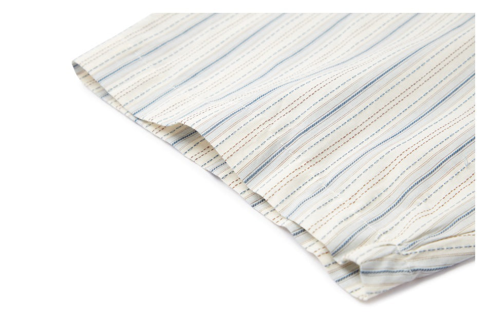 Close-up of the hem on cream fabric with fine blue and brown stripes.