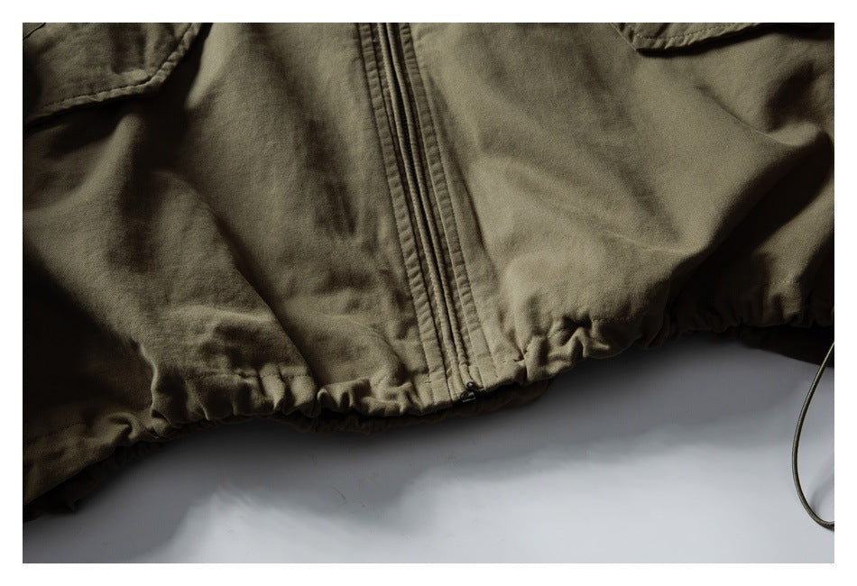 Close-up of an olive jacket's front zipper and gathered elastic hem.