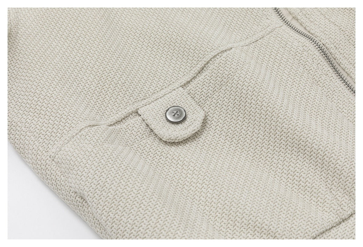 Close-up of an ivory textured jacket with a buttoned flap and part of a metal zipper.