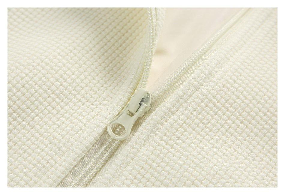 Close-up of a cream zipper and pull set into cream textured fabric.