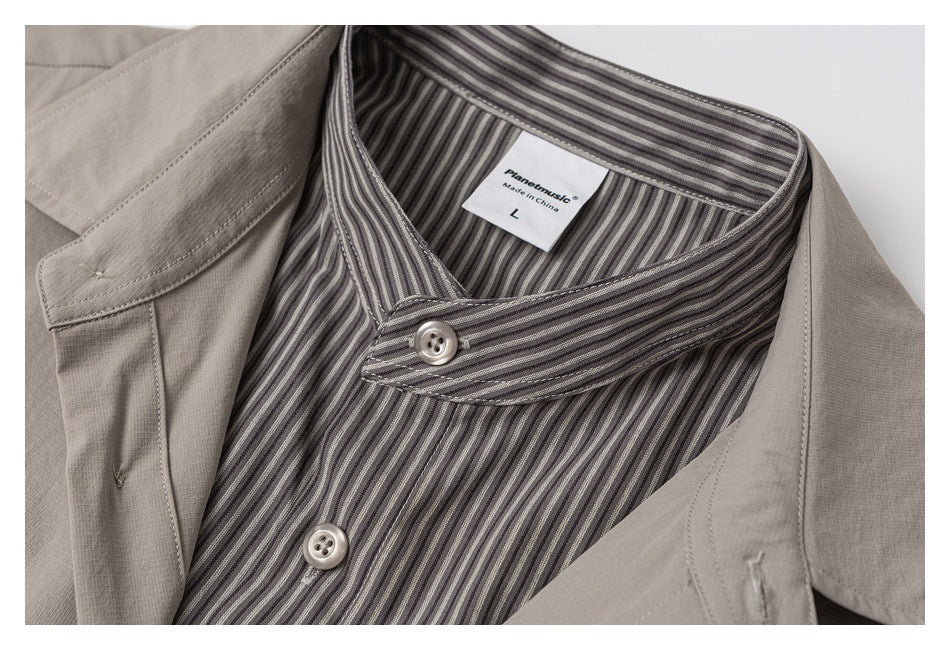 Close-up of a taupe shirt collar with a gray striped inner collar and buttons.