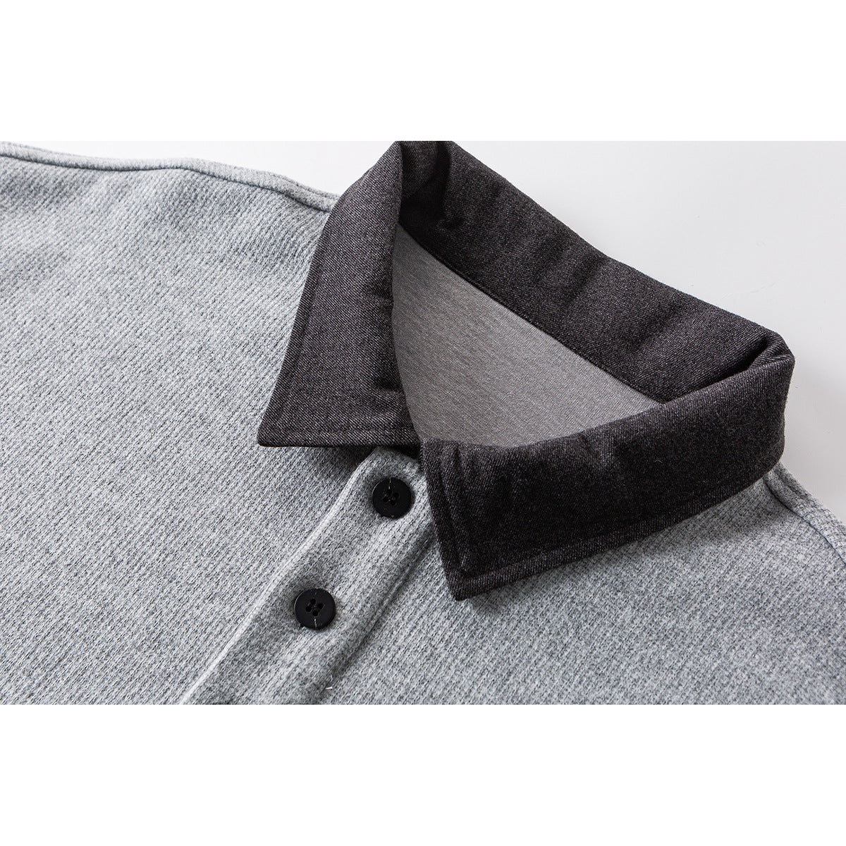 Close-up of a light gray shirt with a dark charcoal collar and two black placket buttons.