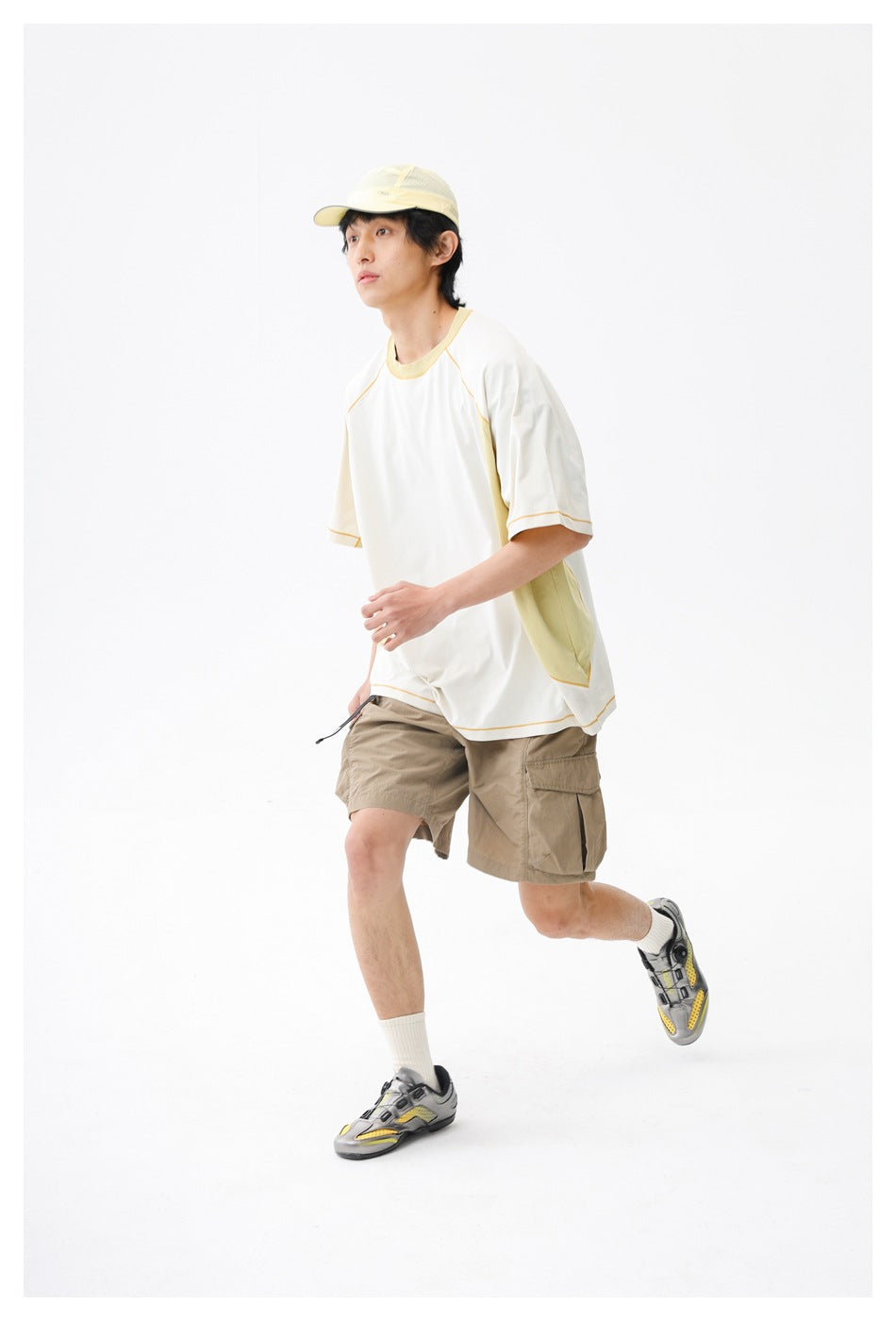 Model in motion wearing a white and pale yellow color-block top and beige cargo shorts.