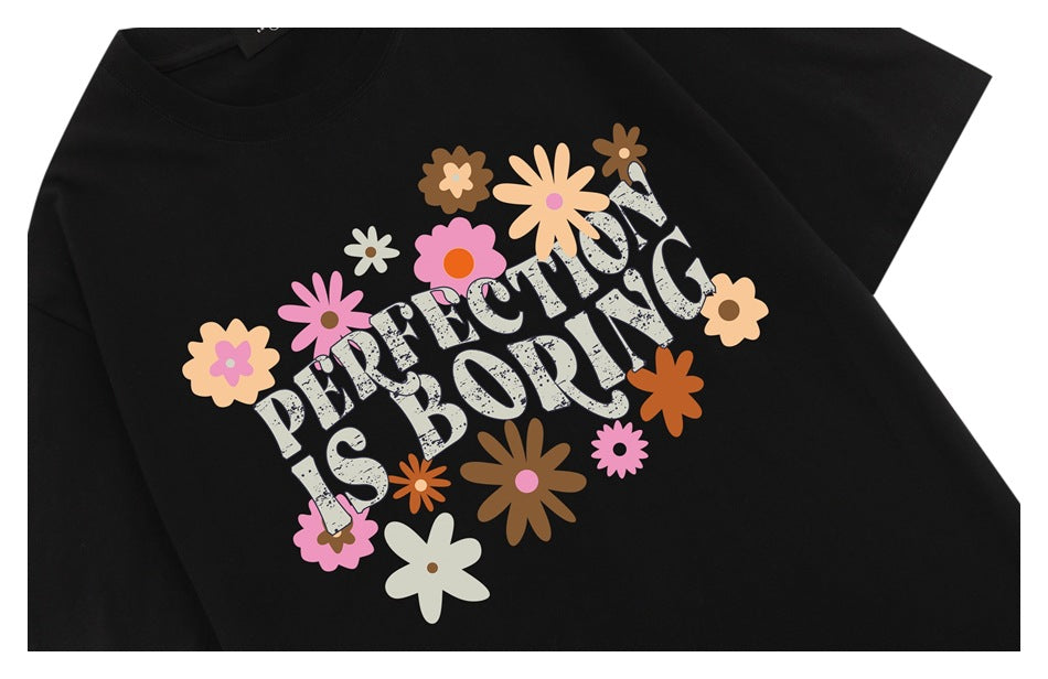 Close-up of a black T-shirt with a colorful flower graphic and the words “PERFECTION IS BORING.”