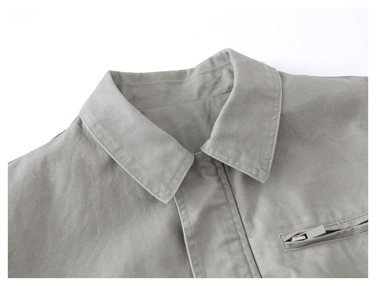 Close-up of a light gray jacket's pointed collar, front placket, and narrow chest pocket.