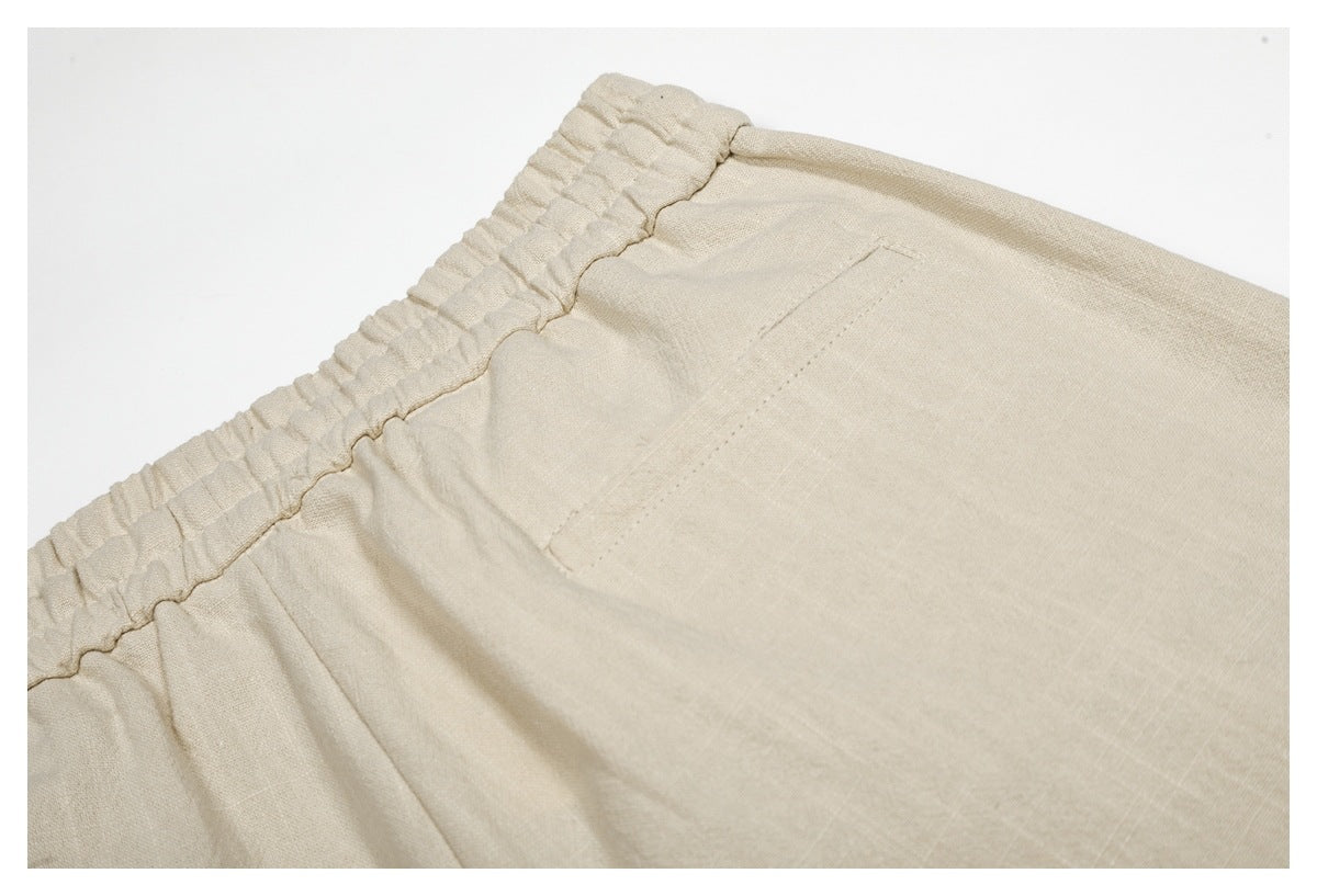 Close-up of a cream garment showing a gathered elastic waistband and stitched pocket.