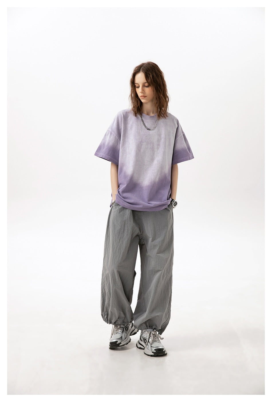 Model wearing an oversized lavender washed short-sleeve T-shirt with loose gray trousers.
