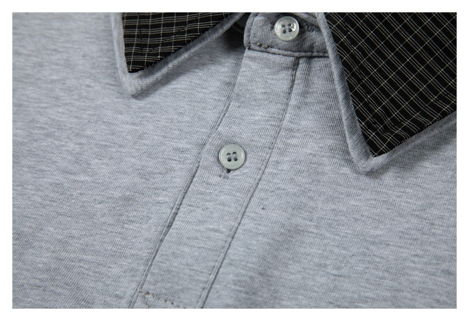 Close-up of a gray garment with a black plaid collar and two light buttons.