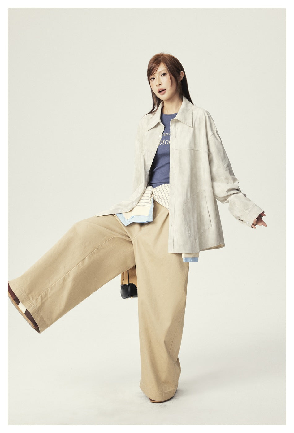 Full-length view of a model wearing a light beige oversized shirt jacket with tan wide-leg trousers.
