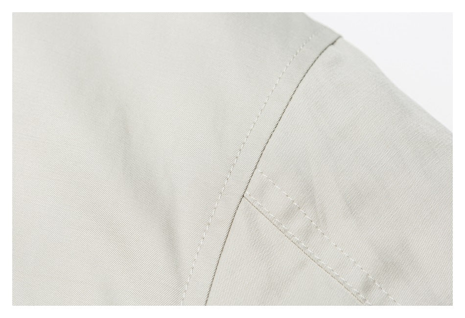 Close-up of the shoulder seam and stitching on a light beige jacket.