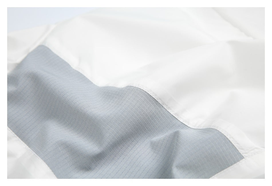 Close-up of a gray textured panel stitched into a white garment.
