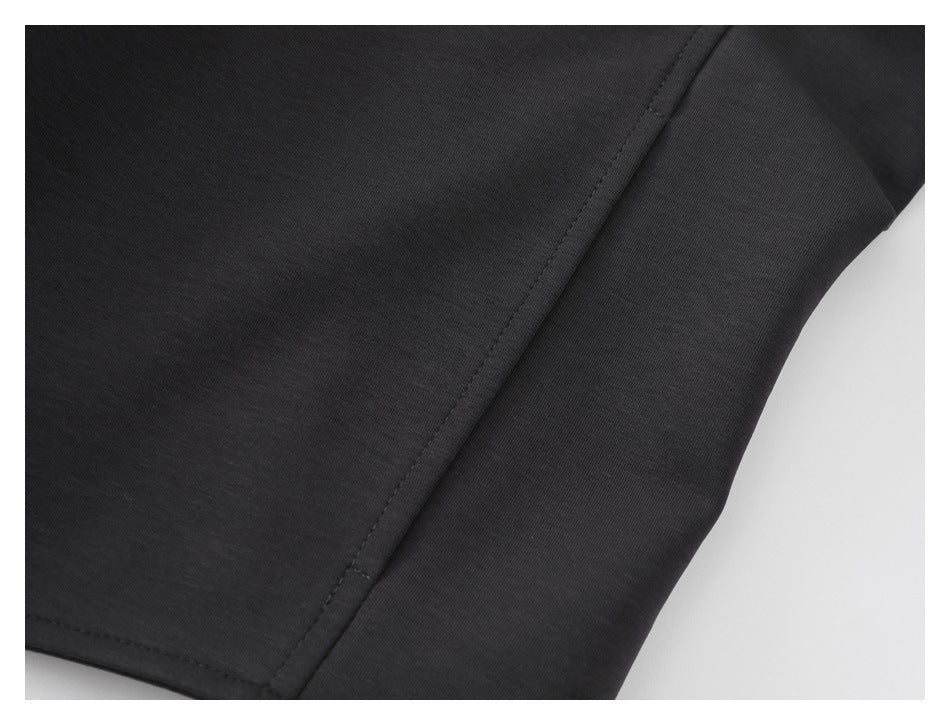Close-up of a charcoal garment side seam and curved stitched panel edge.