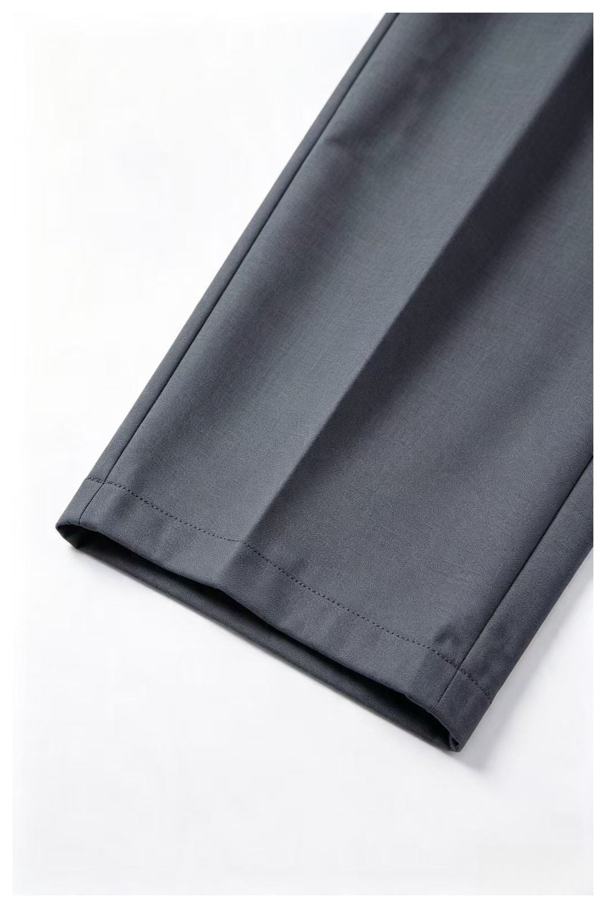 Close-up of a charcoal-gray trouser leg showing its stitched hem and folded cuff edge.