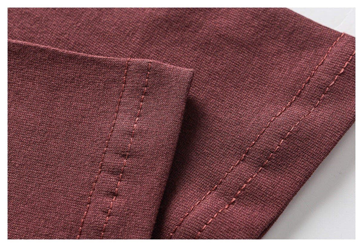 Close-up of burgundy garment fabric showing a folded edge and parallel rows of stitching.