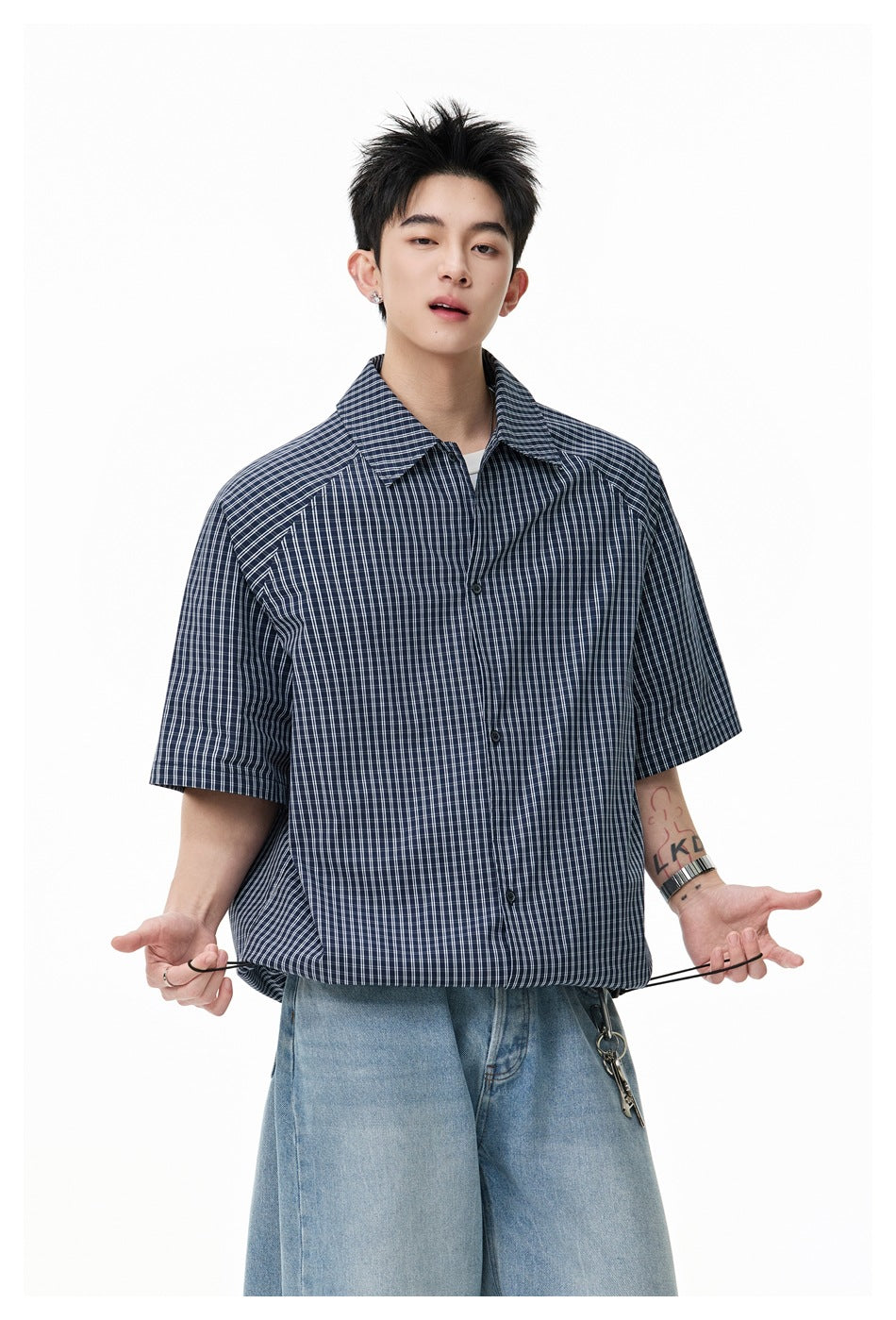 Model wearing a dark navy short-sleeve shirt with a fine white plaid pattern and adjustable drawcord hem.