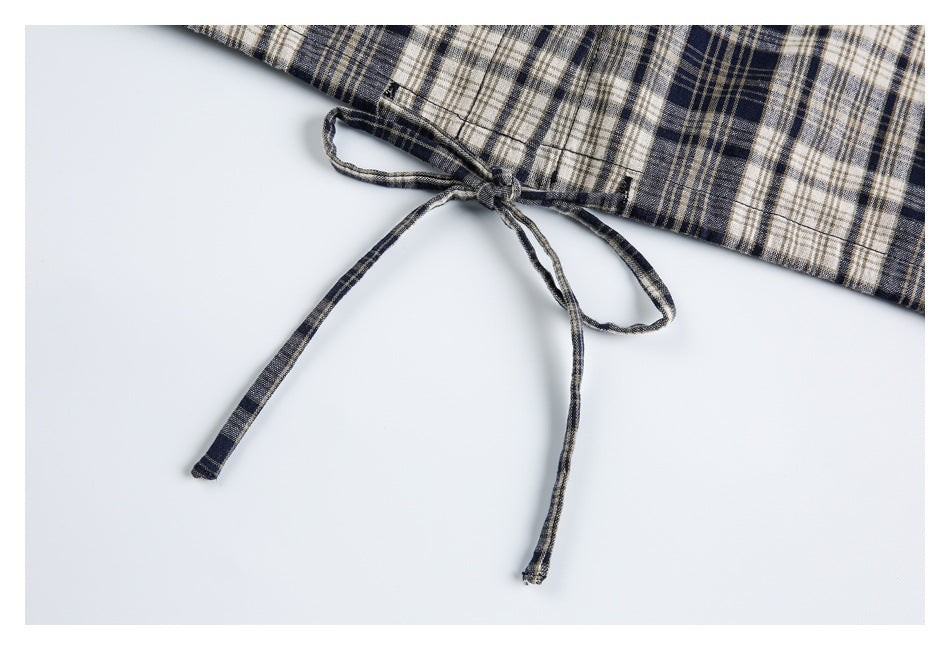 Close-up of a tied drawstring at the edge of navy, cream, and tan plaid fabric.