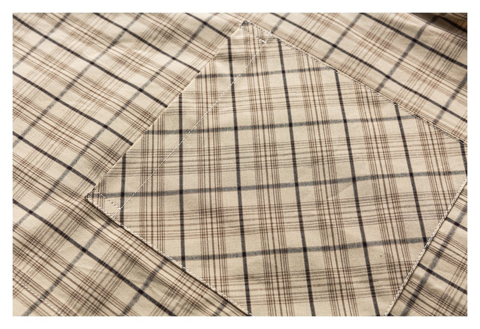 Close-up of a beige plaid shirt’s stitched chest pocket.