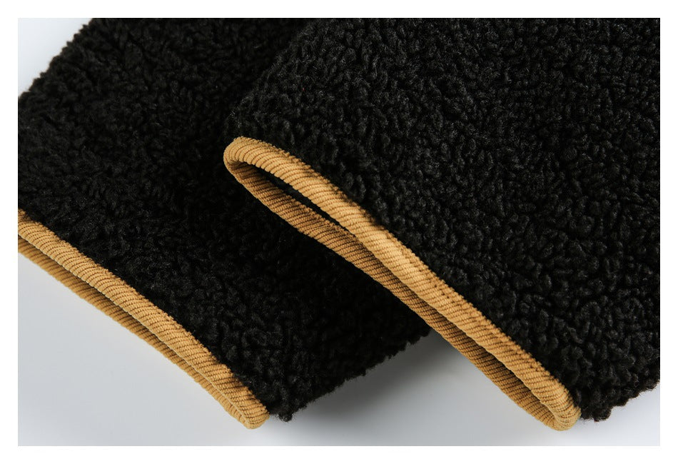 Close-up of black textured fabric with tan piping along two curved edges.