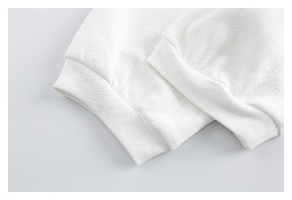 Close-up of white garment fabric showing a folded, stitched edge and hem.