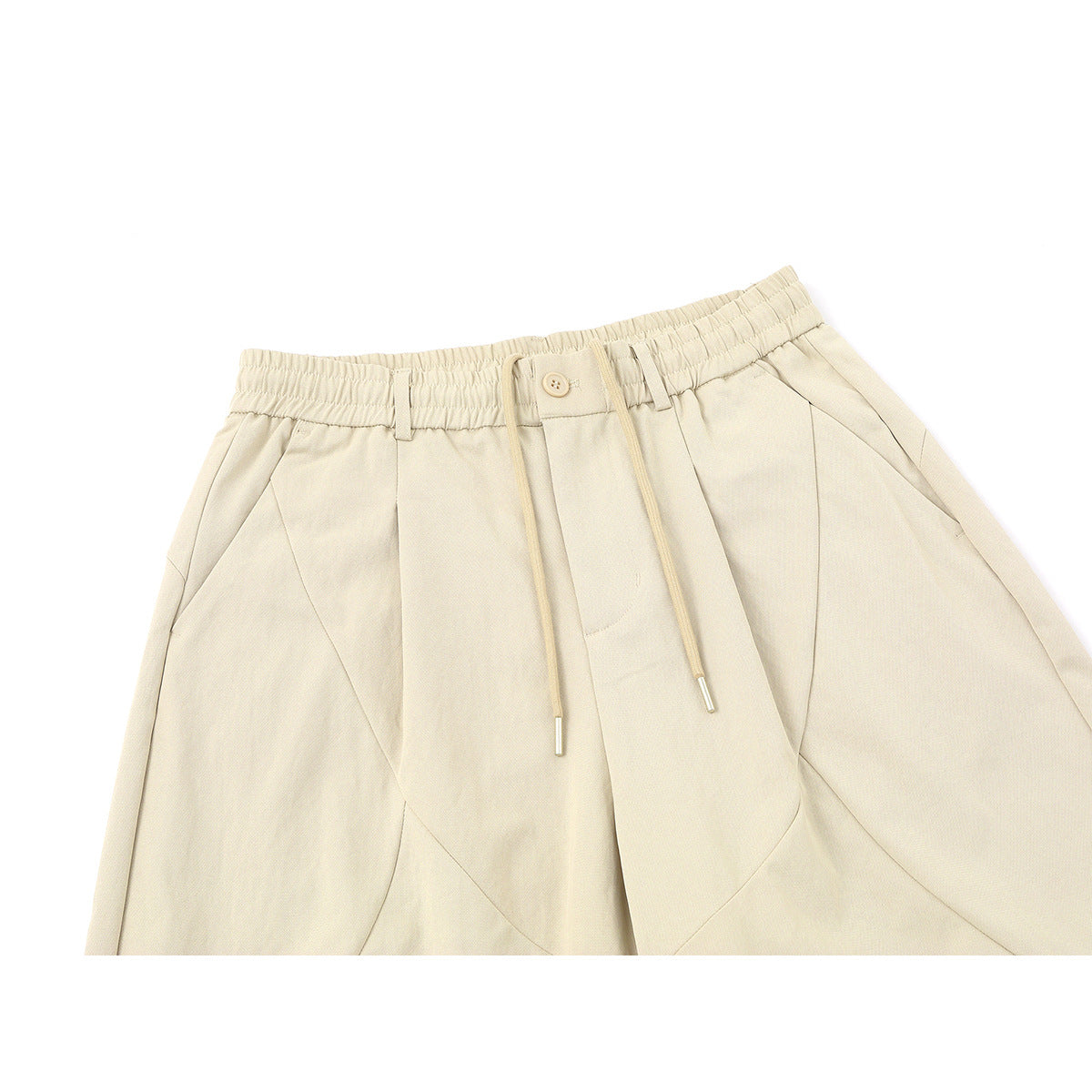 Close-up of cream trousers with an elastic waistband, button, drawstrings, and angled front pockets.