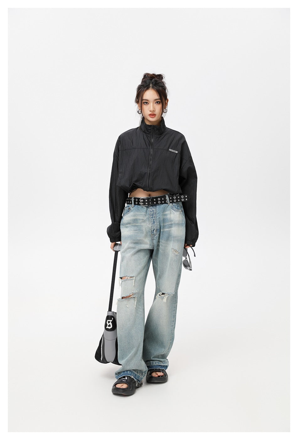 Model wearing a black cropped zip-up jacket with a high collar and light ripped jeans.