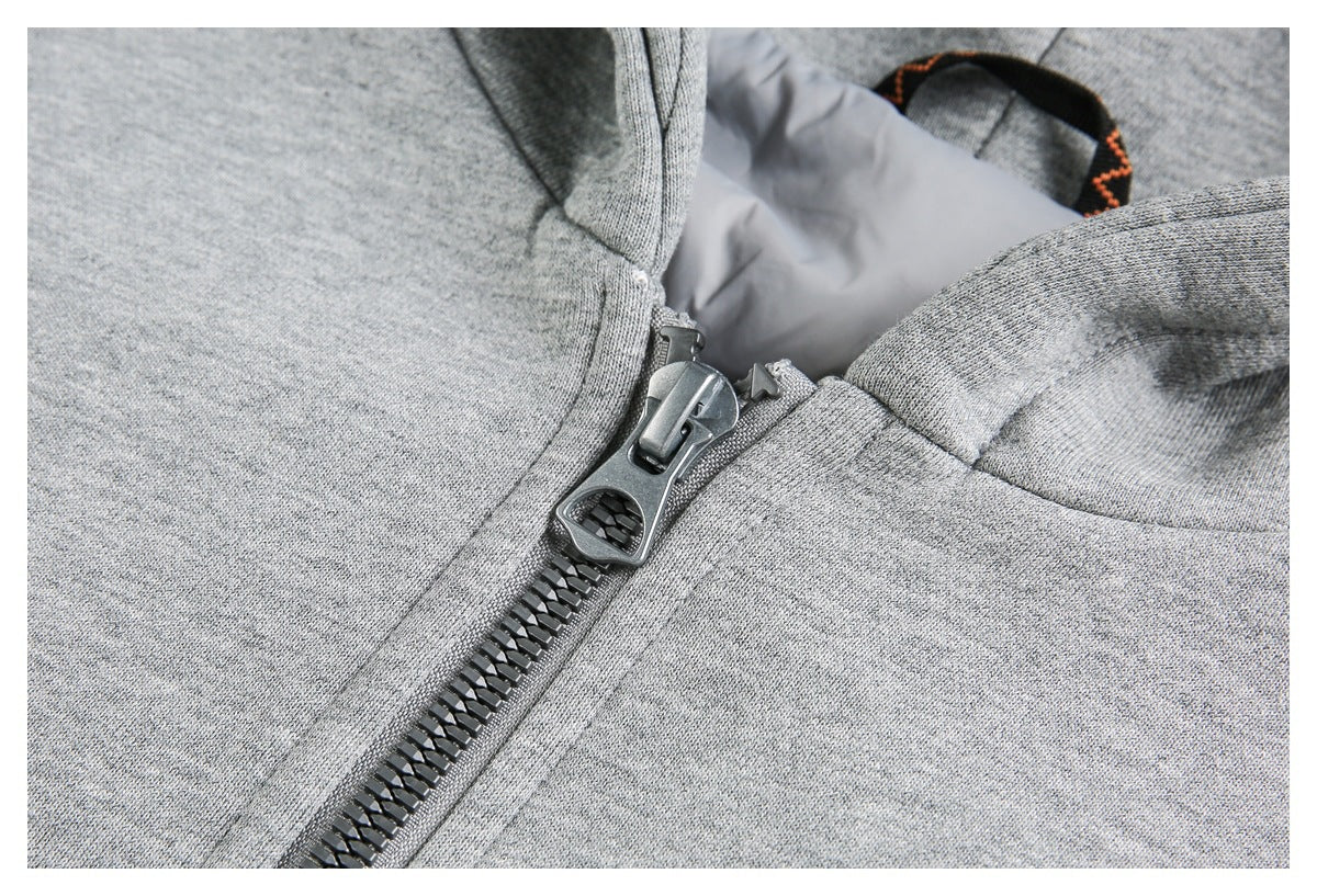 Close-up of a gray sweatshirt’s chunky dark front zipper and surrounding seams.