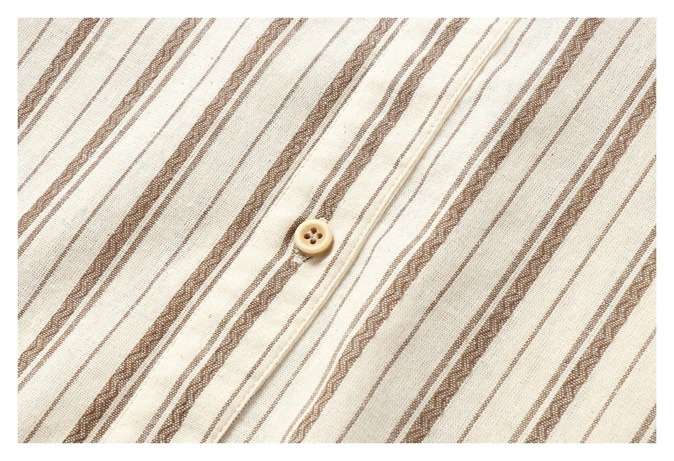 Close-up of a tan button on the placket of a cream shirt with brown stripes.