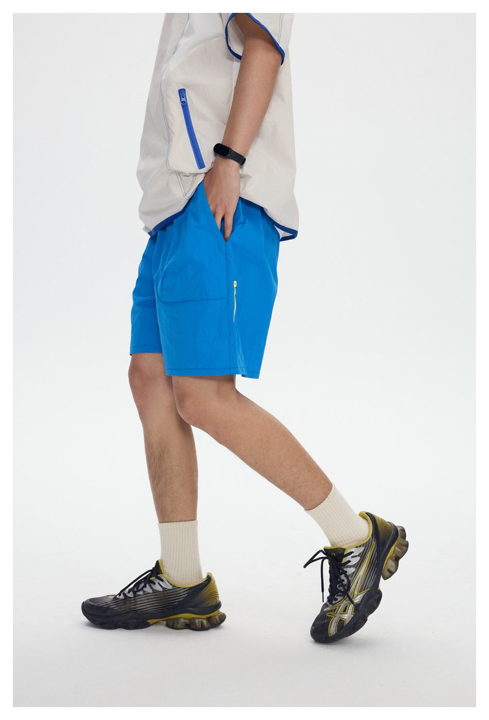 Close view of bright blue shorts with a small side zipper pocket, worn with an off-white top with blue trim.