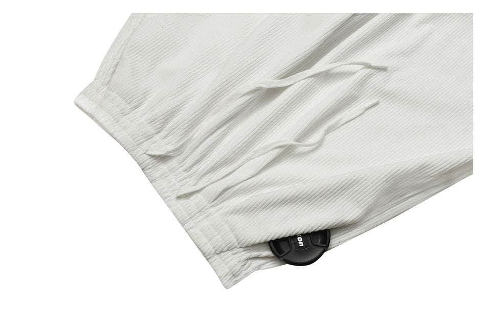 Close-up of the gathered waistband and white drawstrings on ribbed white pants.