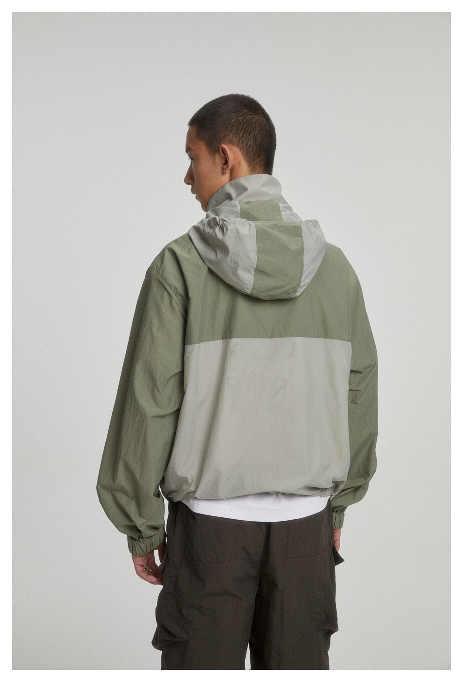 Model wearing the olive and light gray hooded jacket, shown from the back.