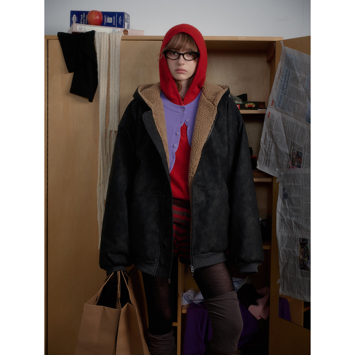 Front view of a model in an oversized black zip jacket with tan sherpa-style lining and dark ribbed cuffs and hem.