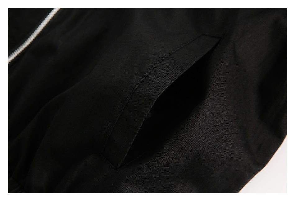 Close-up of a slanted pocket opening on black fabric beside a partial silver zipper.