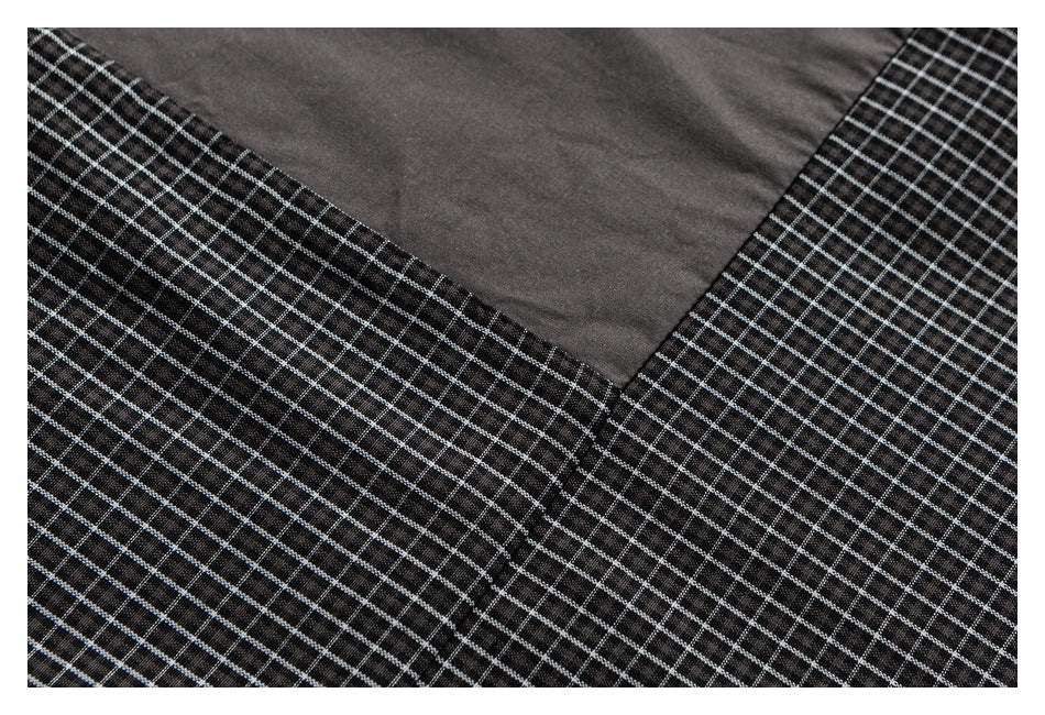 Close-up of black fabric with a fine white grid pattern meeting a solid charcoal panel at a seam.