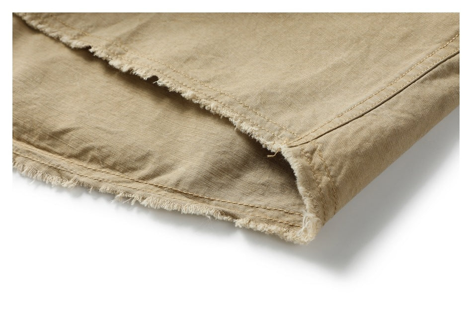 Close-up of the tan shirt's raw, frayed hem and seam stitching.