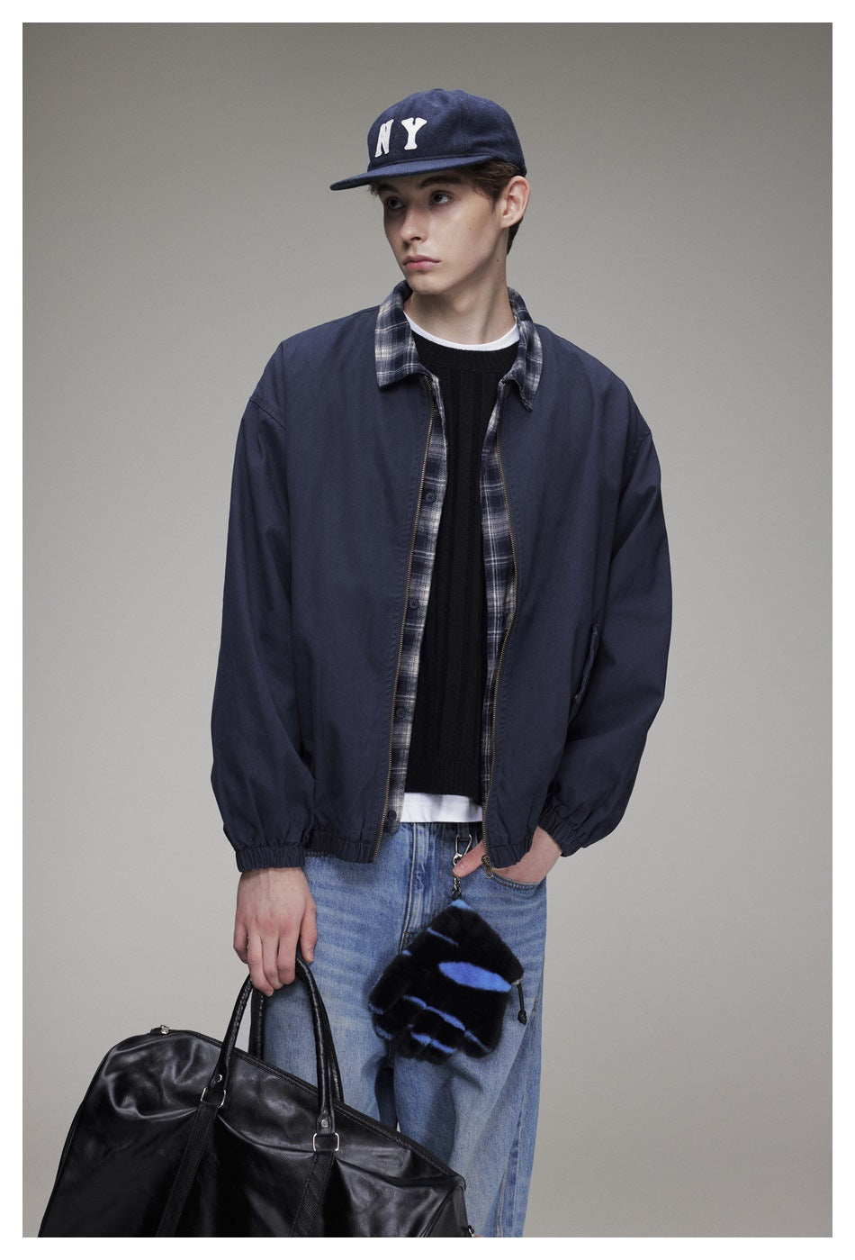 Front view of a model wearing a navy zip jacket with plaid trim, elastic cuffs, and hem.