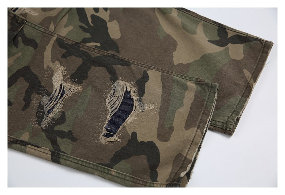 Partial flat lay of camouflage pants showing two frayed tears and a stitched hem.