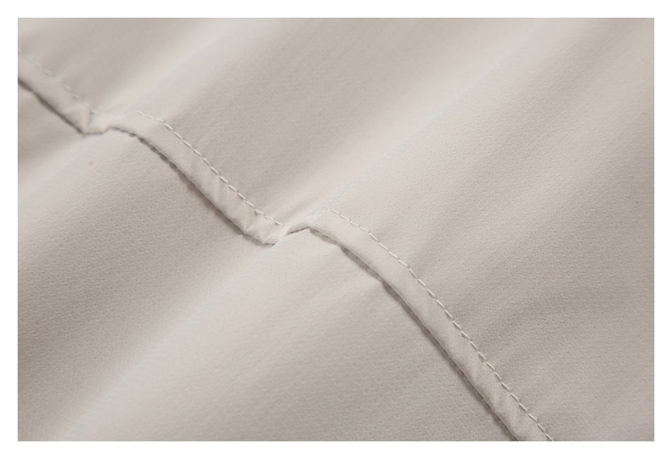 Close-up of light beige fabric with a folded seam and visible stitching.