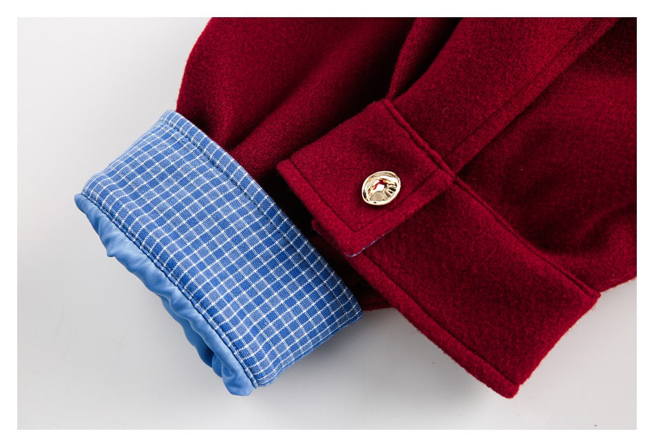 Close-up of a burgundy sleeve cuff with blue checked lining and a gold-tone button.