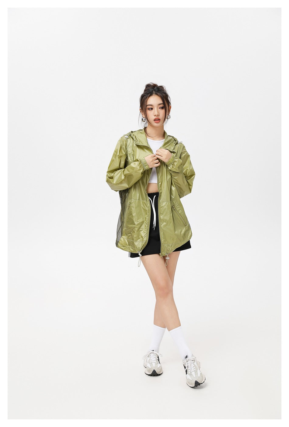 Model wearing an olive hooded jacket open over a white top, with a front zipper, zip pockets and mesh side panels.