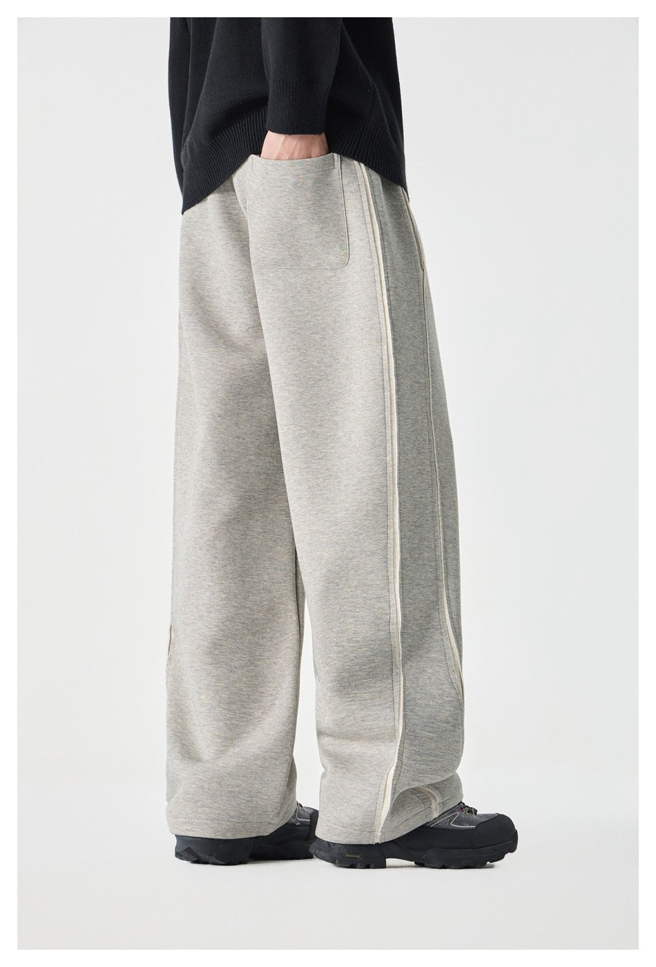 Side view of a model wearing light gray wide-leg pants, showing a patch pocket and long side seams.